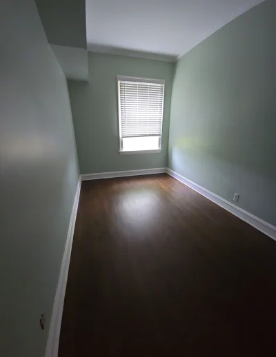 Freshly renovated small bedroom with green walls and hardwood flooring